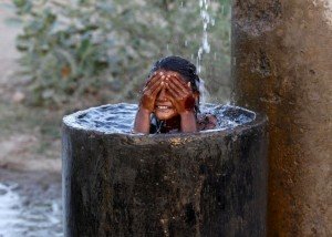 A girl bathes to cool off herself with water that is leaking from a broken pipe valve on a hot summer day on the outskirts of Ahmedabad, India, May 18, 2015. Temperature in Ahmedabad on Monday reached 44 degrees Celsius (111.2 degrees Fahrenheit), according to India's metrological department website. REUTERS/Amit Dave       TPX IMAGES OF THE DAY      - RTX1DISN