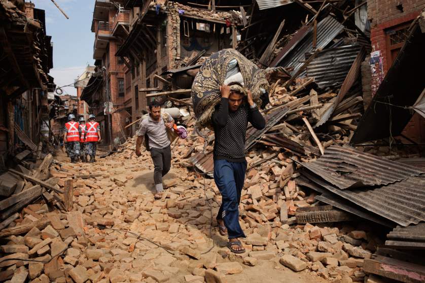 A Nepali man carries recovered belongings through the street in the ancient city of Bhaktapur in the Kathmandu Valley on April. 28, 2015. Nepal had a severe earthquake on April 25th. Photo by Adam Ferguson for Time